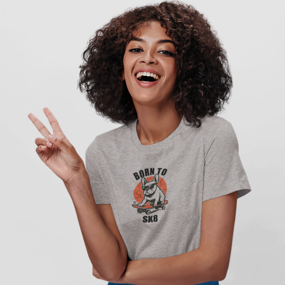 Woman in a heather grey organic cotton T-shirt featuring a French Bulldog wearing sunglasses on a red skateboard with “Born to Sk8” text in bold streetwear style