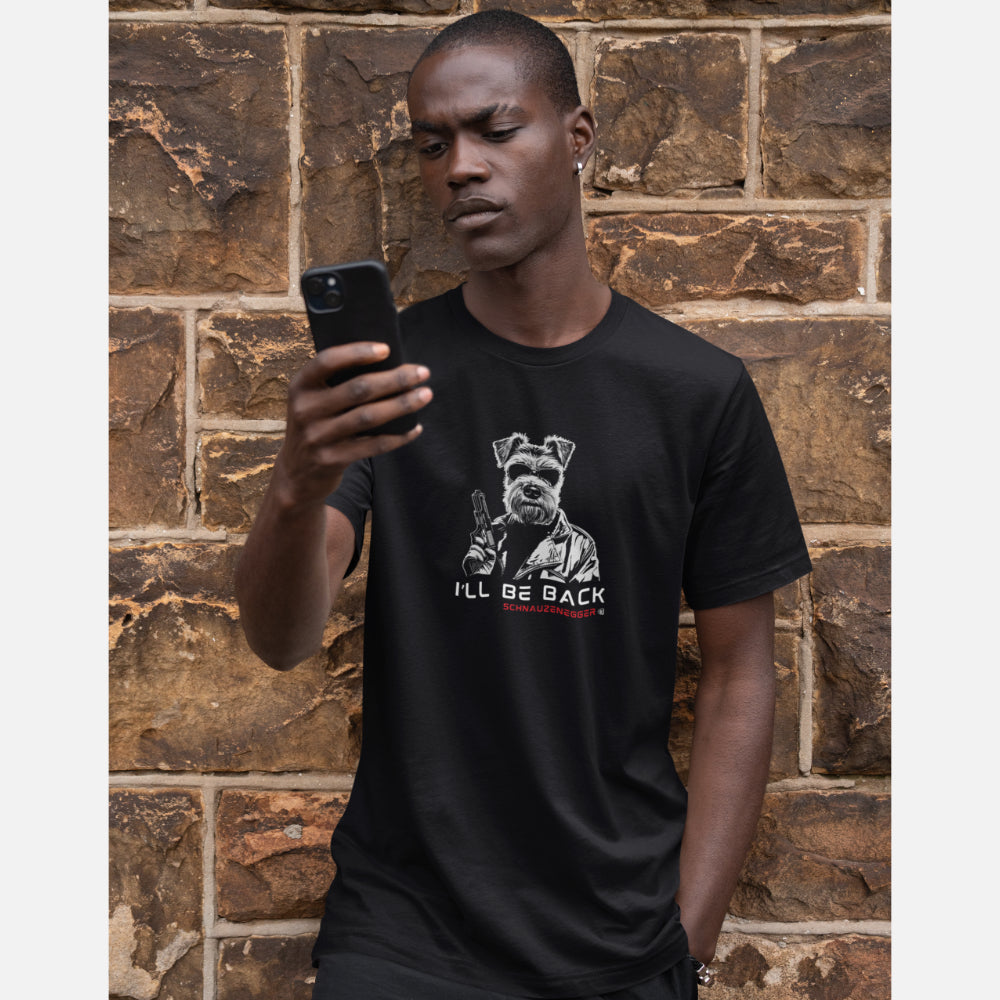 Man in a black T-shirt featuring a Miniature Schnauzer in Terminator style with sunglasses, leather jacket, and gun, slogan “I’LL BE BACK,” and text “SCHNAUZENEGGER.”