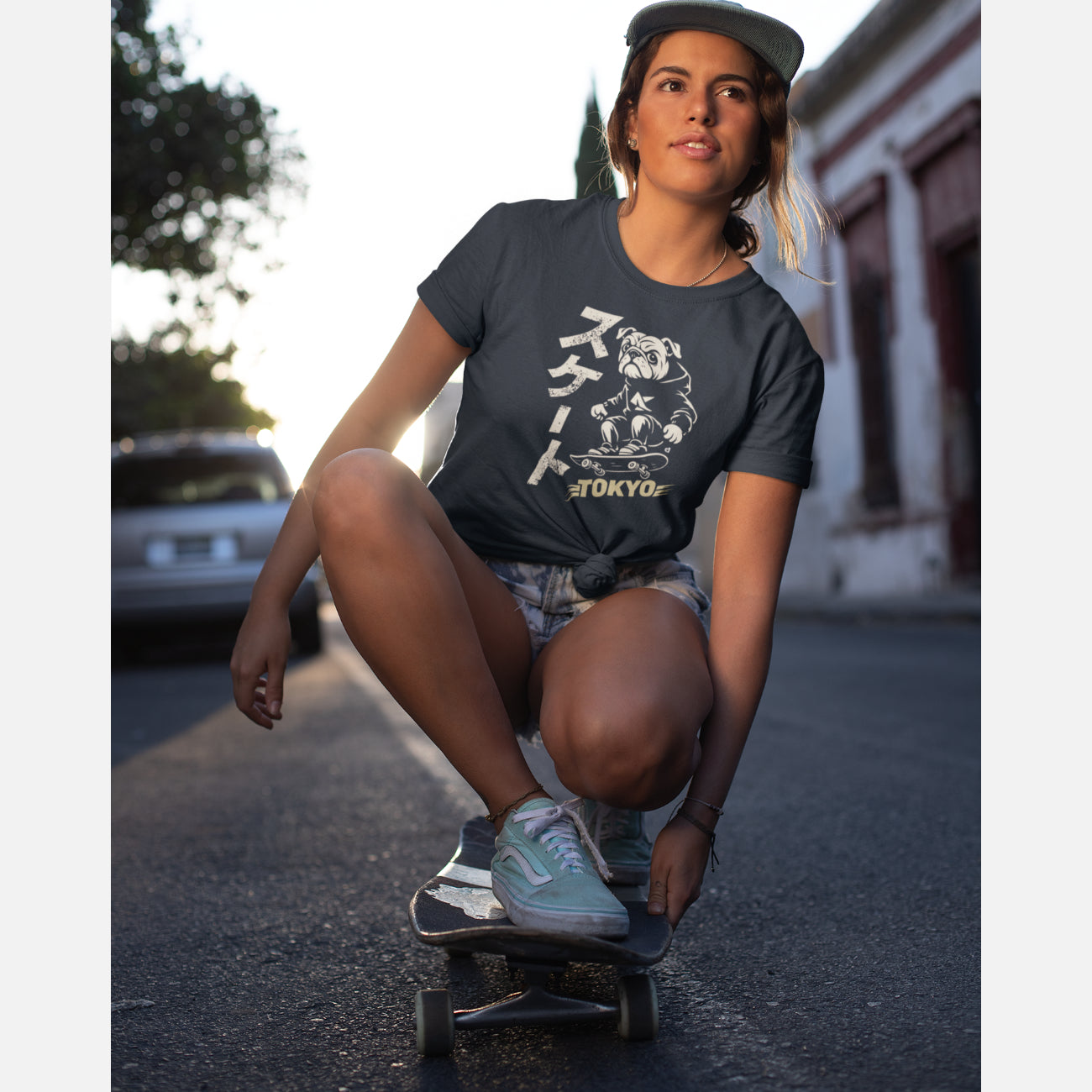 Women in an unisex navy T-shirt featuring a British Bulldog skateboarder in a streetwear illustration, with vertical Japanese “Skate” text and a muted yellow Tokyo graphic.