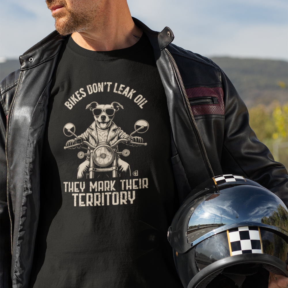 Man in a black T-shirt featuring a biker-style Jack Russell Terrier riding a motorcycle, wearing sunglasses and a leather jacket, with the slogan “Bikes Don’t Leak Oil, They Mark Their Territory” printed above and below the illustration in a vintage font.
