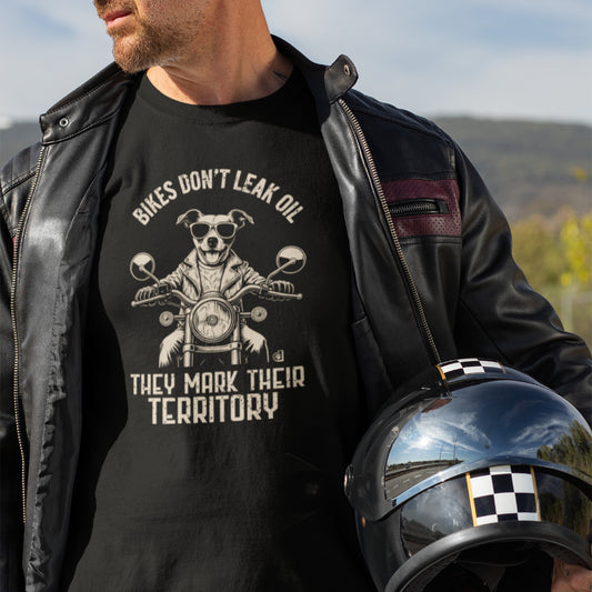Man in a black T-shirt featuring a biker-style Jack Russell Terrier riding a motorcycle, wearing sunglasses and a leather jacket, with the slogan “Bikes Don’t Leak Oil, They Mark Their Territory” printed above and below the illustration in a vintage font.