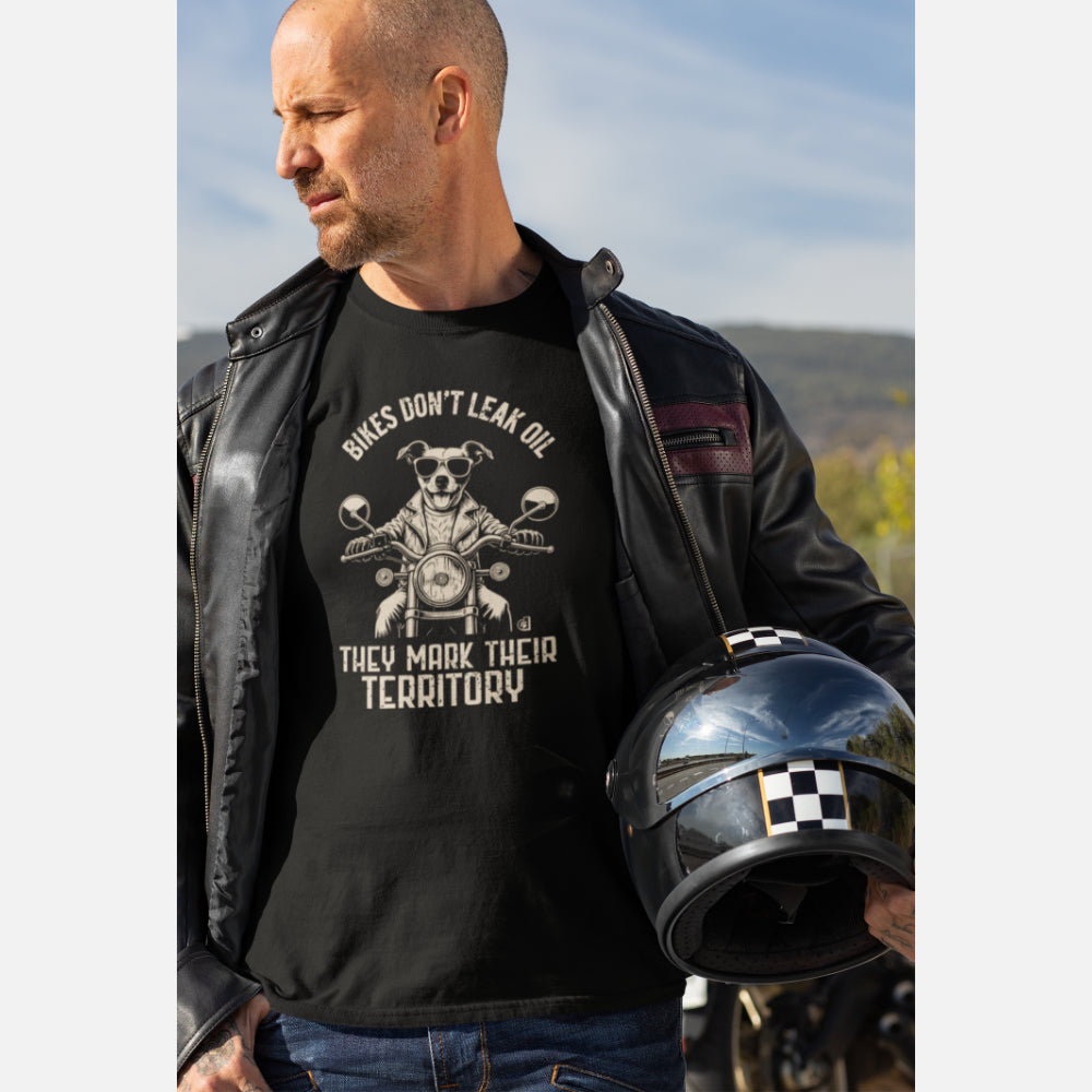 Man in a black T-shirt featuring a biker-style Jack Russell Terrier riding a motorcycle, wearing sunglasses and a leather jacket, with the slogan “Bikes Don’t Leak Oil, They Mark Their Territory” printed above and below the illustration in a vintage font.