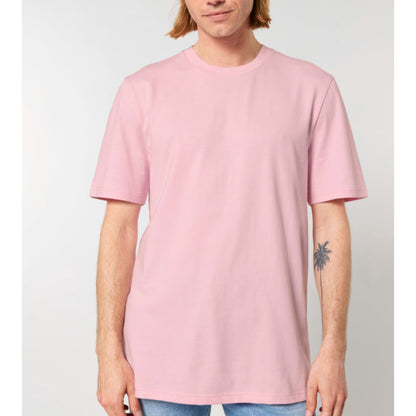 A person wearing a Stanley Stella cotton pink short-sleeve crewneck t-shirt, shown from the chin down against a light grey studio background.