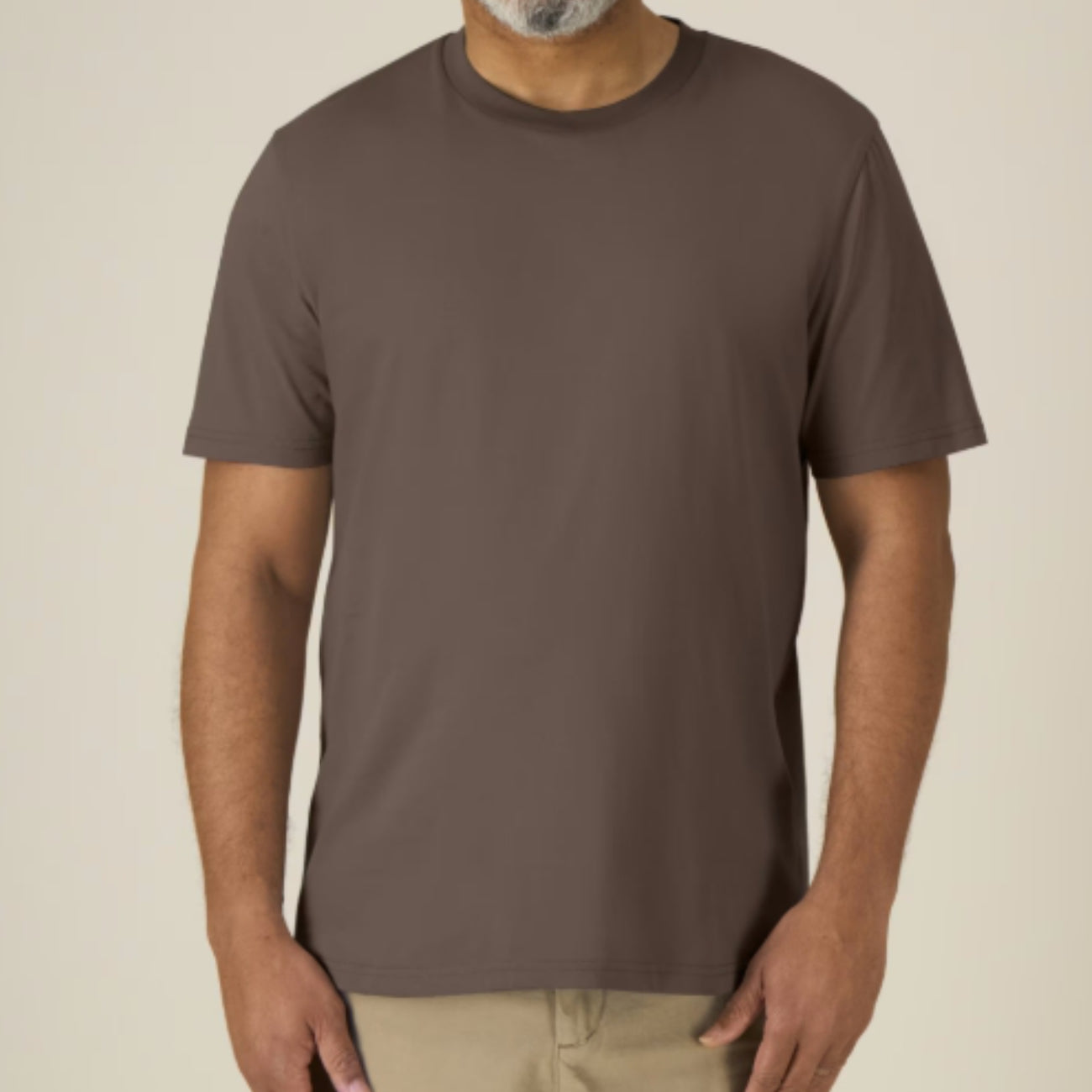 Man wearing a plain Mocha coloured t-shirt against a beige background