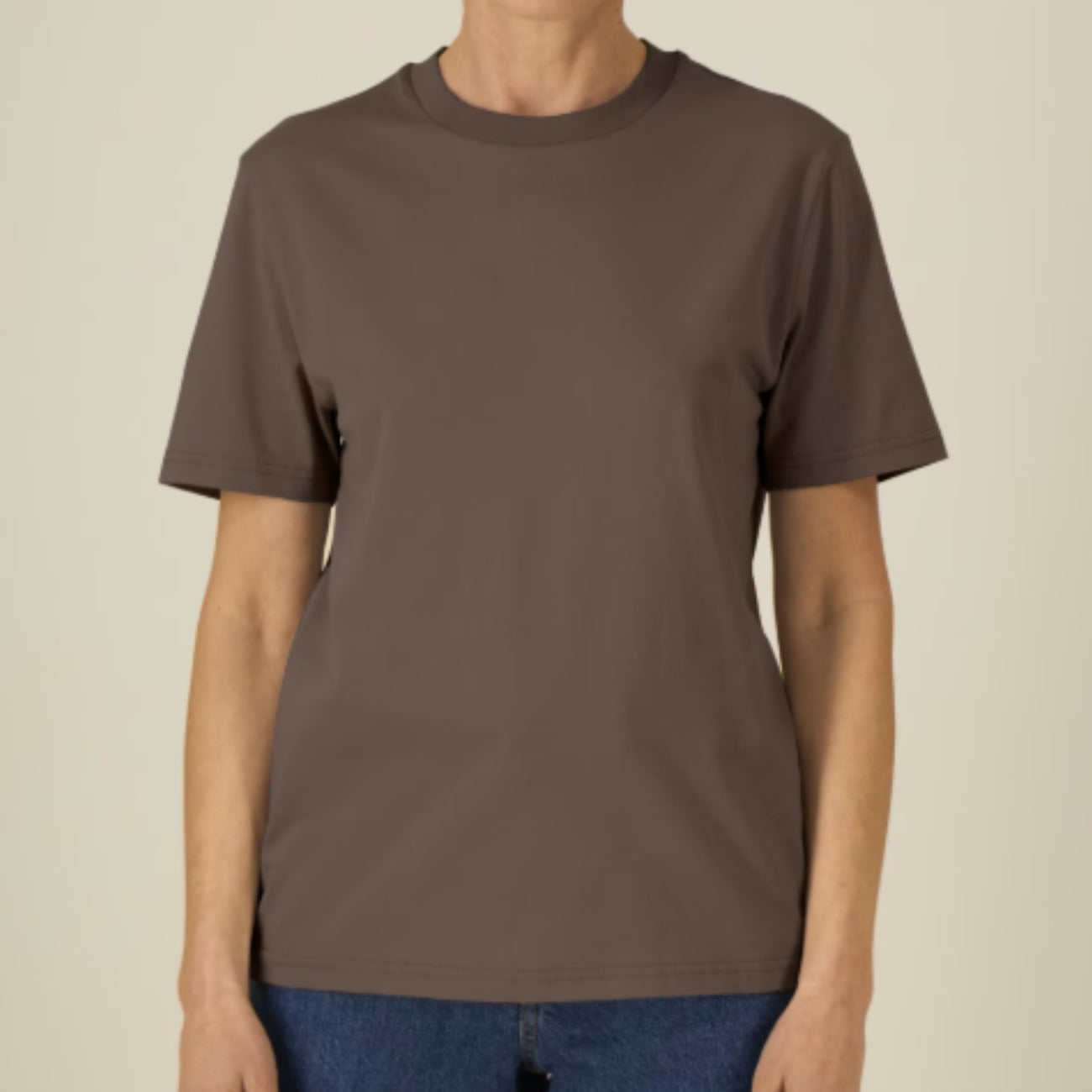 Person wearing a plain Mocha coloured t-shirt on a beige background