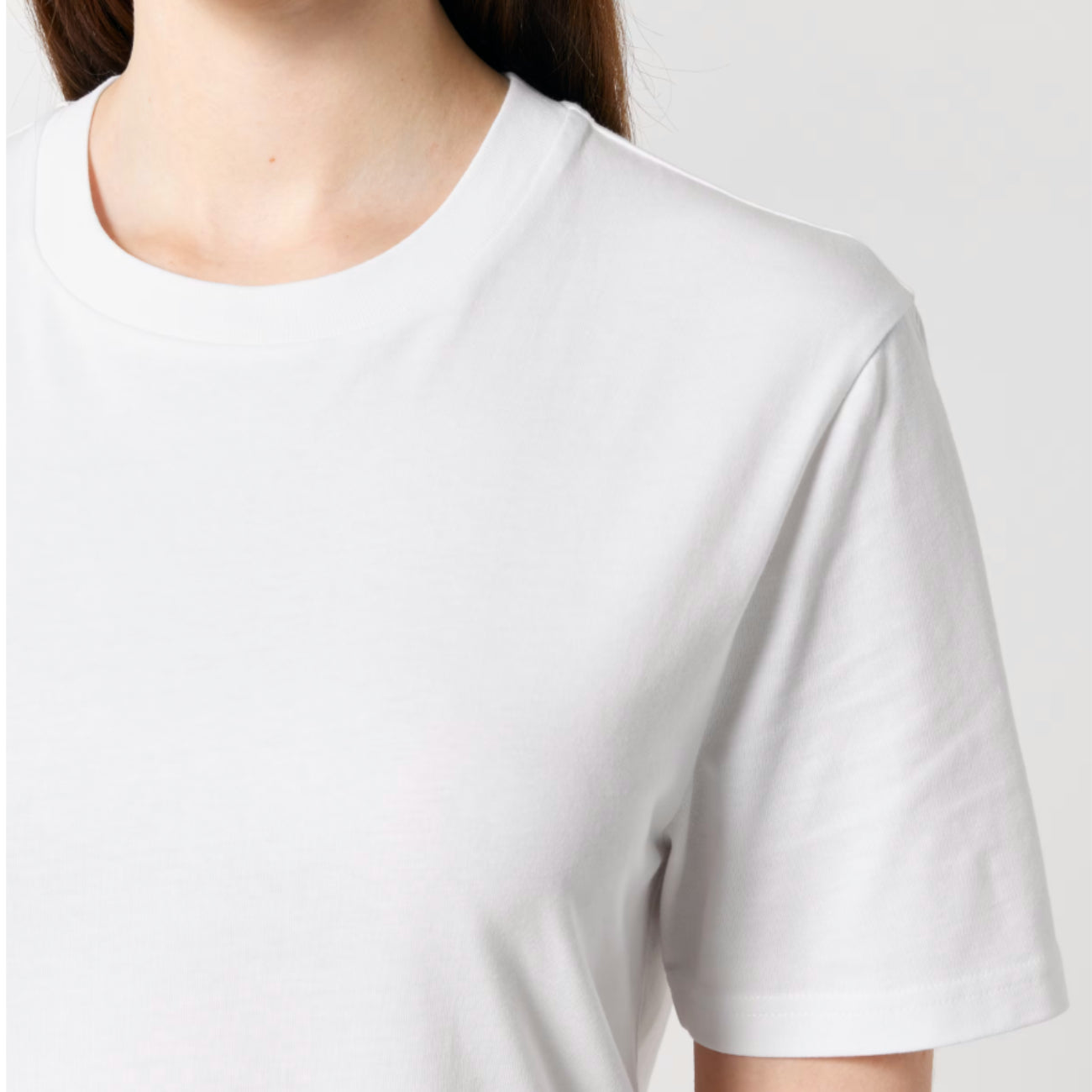 A close-up of a person wearing a Stanley Stella white short-sleeve crew-neck t-shirt against a light grey background.