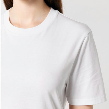 A close-up of a person wearing a Stanley Stella white short-sleeve crew-neck t-shirt against a light grey background.